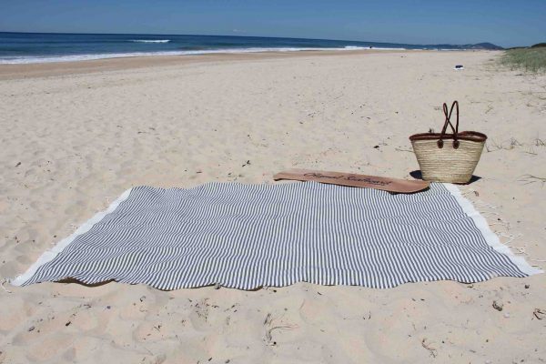 Beach towel at the beach with basket and surf board
